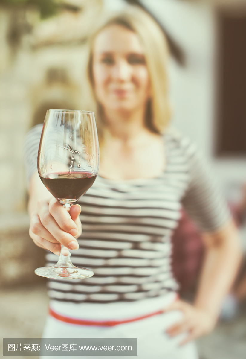 一個女人在室外遞上一杯紅酒。復古的效果。