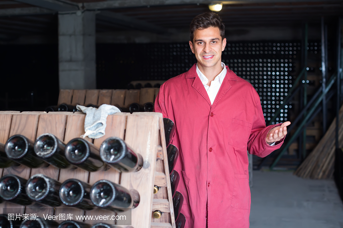 微笑的男人穿著制服工作與瓶子儲(chǔ)存架